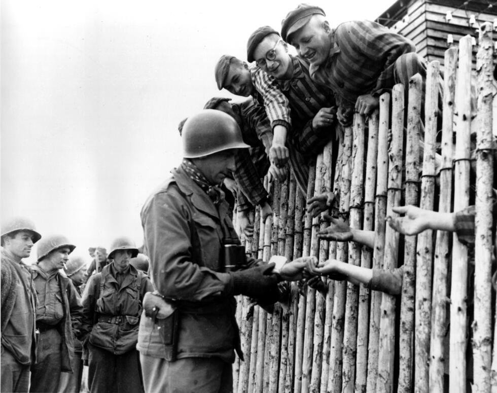 Cette photo montre un soldat américain tendant la main aux détenus du camp de concentration nazi libéré de Dachau, en Allemagne, en avril 1945, pendant la Seconde Guerre mondiale.
