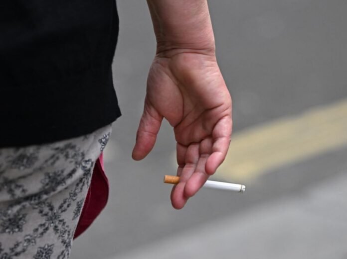 Une personne de dos avec une cigarette à la main. 