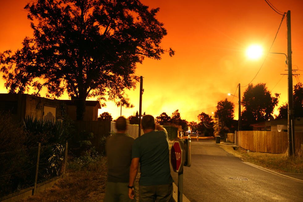 En images : près du bassin d'Arcachon, le feu s'attaque à nouveau à la forêt des Landes 8 Des habitants face au ciel illuminé par le violent incendie au Porge, le 23 juillet 2026.