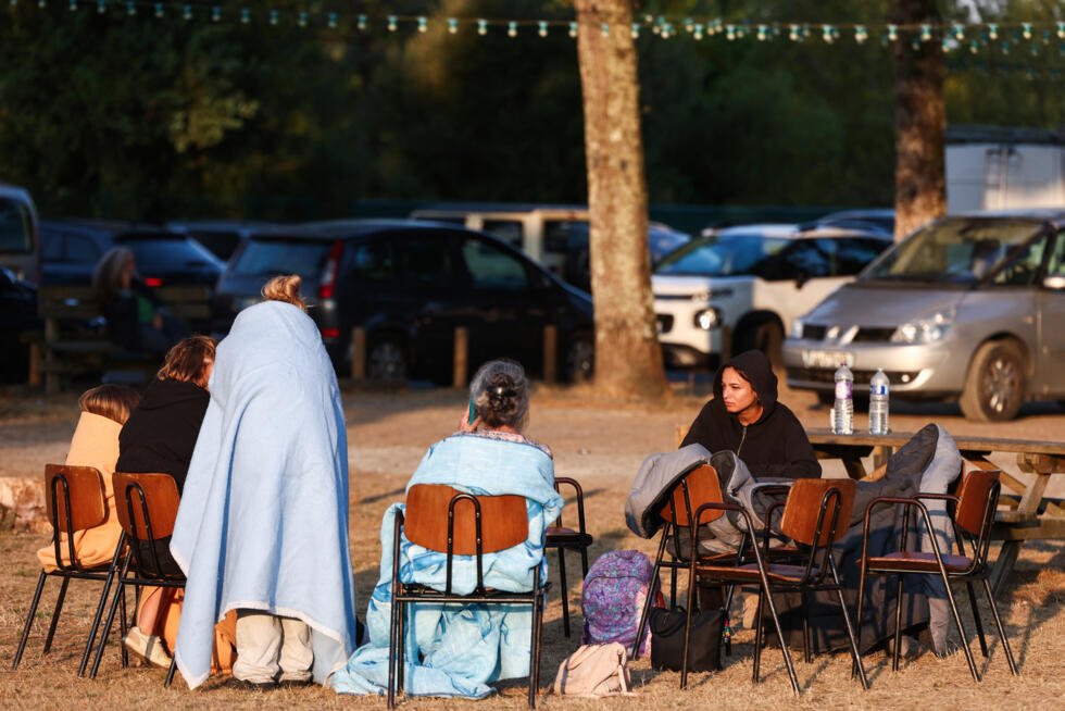 En images : près du bassin d'Arcachon, le feu s'attaque à nouveau à la forêt des Landes 5 Des habitants évacués à cause de l'incendie assis dans leurs sacs de couchage à l'extérieur à l'heure du petit-déjeuner devant la salle des fêtes Gérard Blanc au Porge, le 23 juillet 2026.