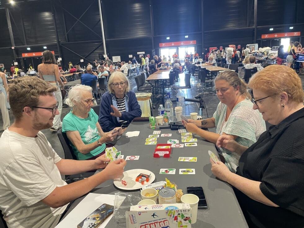 Marilyse joue aux cartes avec des personnes rencontrées au centre des expositions, eux aussi réfugiés des incendies, le 27 juillet 2026